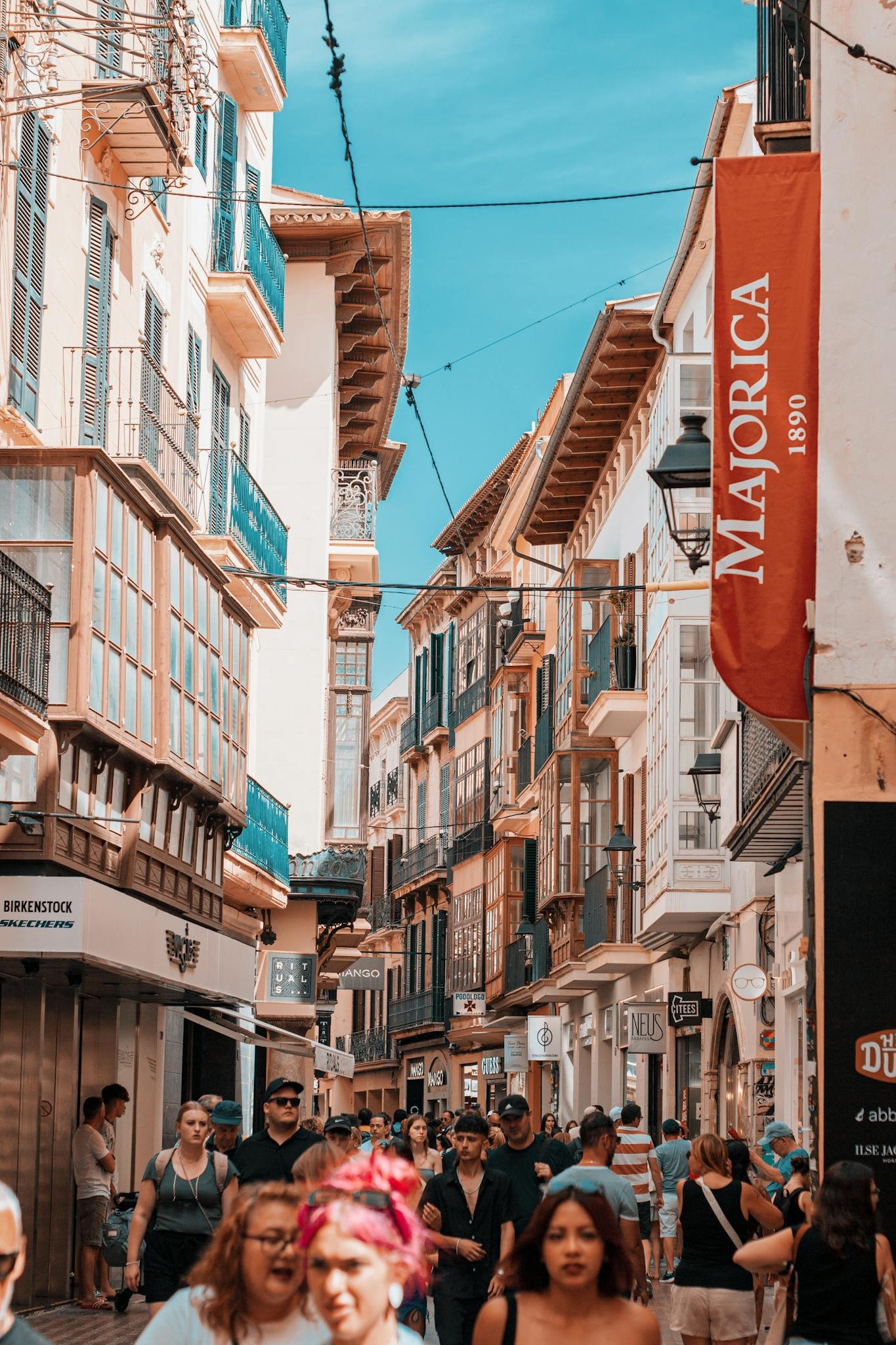 Vibrant summer scene of a busy street in Palma de Mallorca, Spain, featuring historic architecture.
