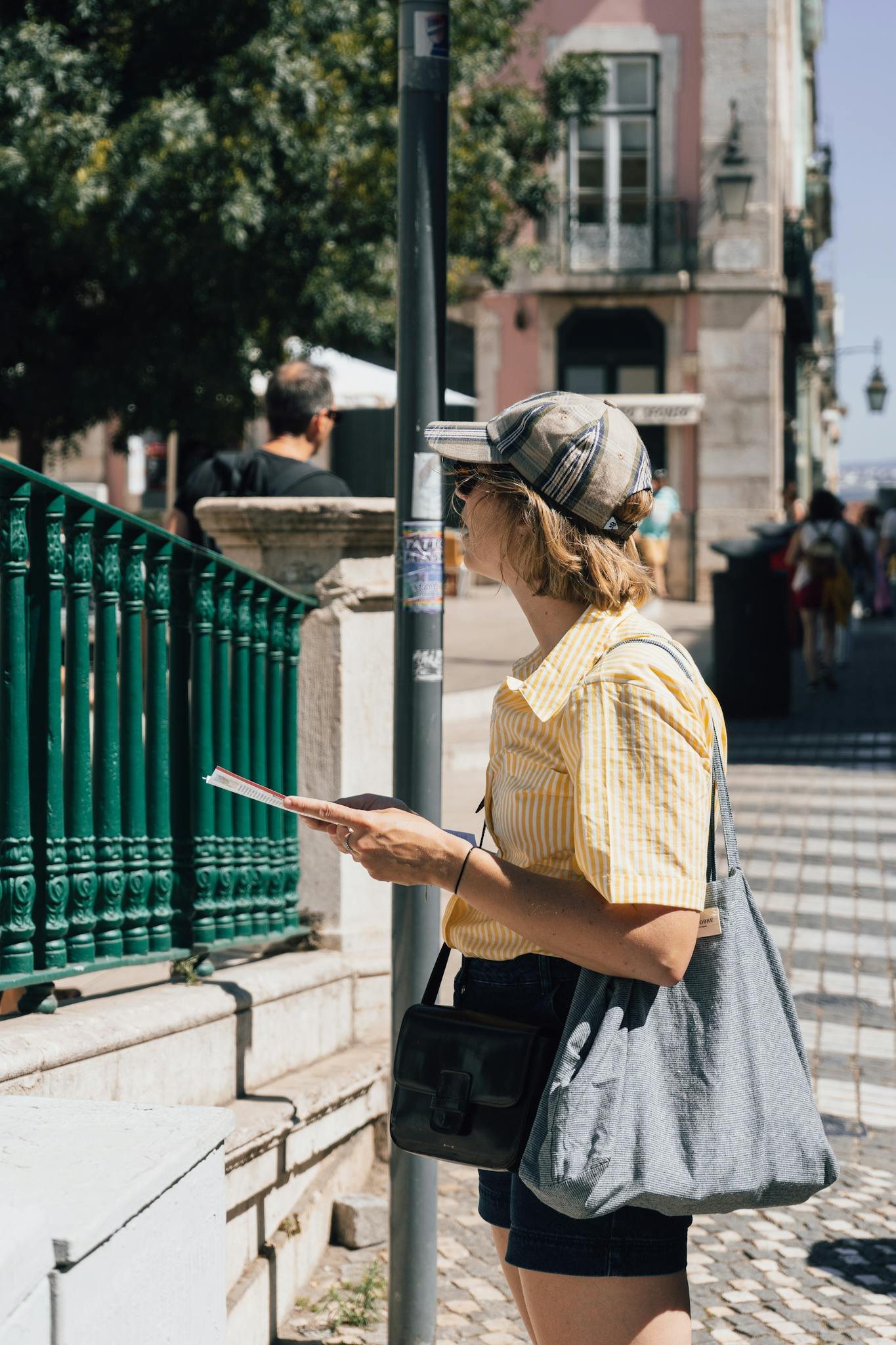 Woman sightseeing in Lisbon, Portugal, holding a guide leaflet on a sunny day.